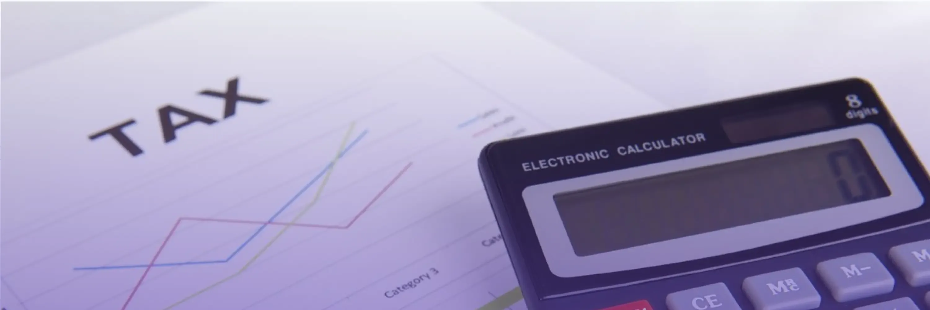 Close-up of a tax document with colorful line charts and a calculator, symbolizing financial analysis under soft purple lighting.